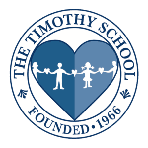 Timothy School Logo. Blue heart surrounded by a circle with The Timothy School written in black and blue lettering.